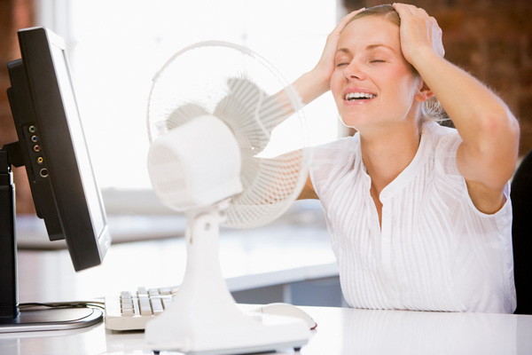 woman sitting in front of fan due to high humidity at home