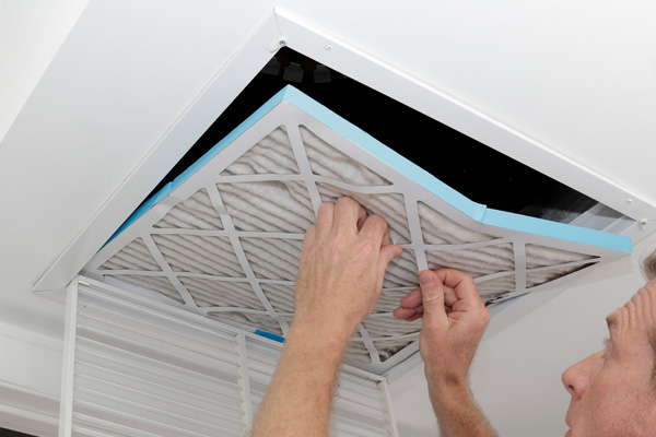 image of a homeowner replacing an hvac air filter to improve indoor air quality