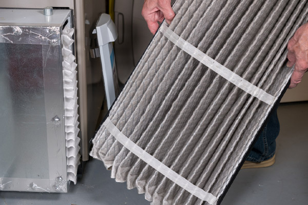 Senior man changing a dirty air filter in a HVAC Furnace