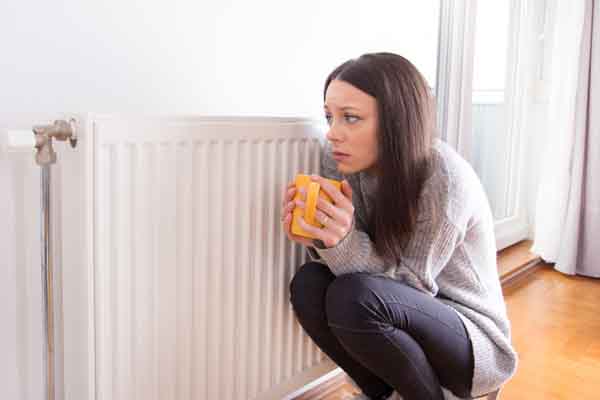 image of a homeowner in front of radiator due to boiler problems