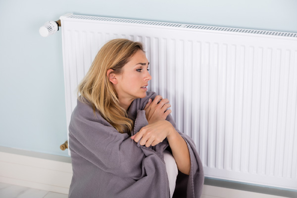 image of a homeowner sitting by radiator due to running out of home heating oil