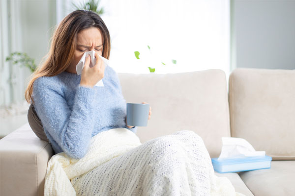 woman sneezing due to poor indoor air quality symptoms