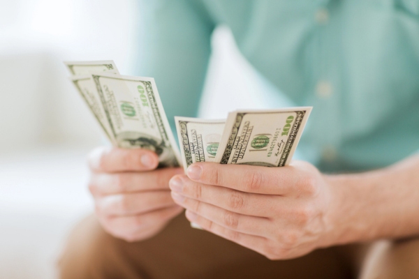 Close up of man counting money at home depicting increased energy expenses