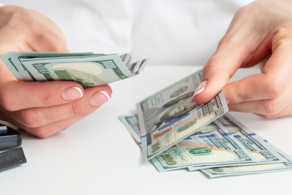 cropped view of a woman's hand counting money depicting financial aspects of new AC