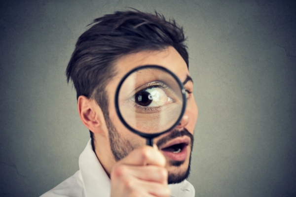 man looking though magnifying glass depicting signs you need to seal air drafts