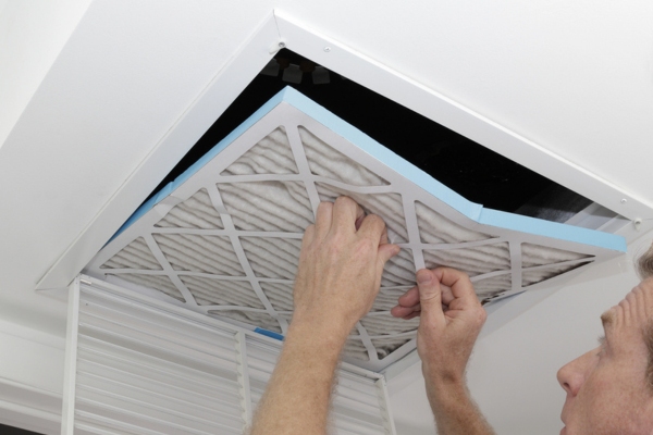 homeowner checking HVAC air filter on the ceiling