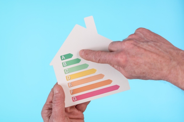 Hands holding a house cutout showing home energy efficiency rating