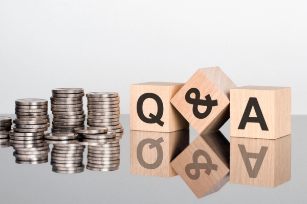 Q&A spelled using wooden letter and symbol cubes beside stacks of coins depicting FAQs About Heating Oil Efficiency