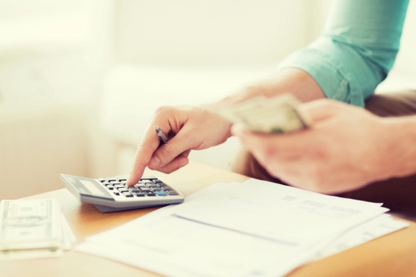 Close up image of a man counting money and making notes depicting increased winter expense