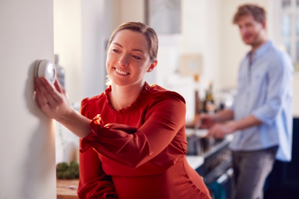 woman adjusting home thermostat preparing for warmer months