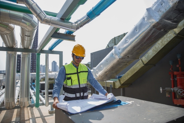 male worker checking building blueprint of HVAC system