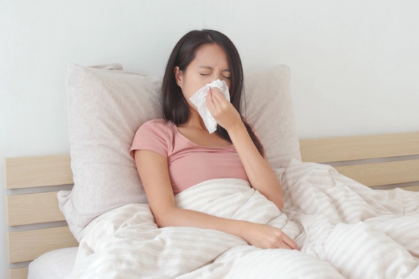 woman blowing nose on a tissue due to AC sickness