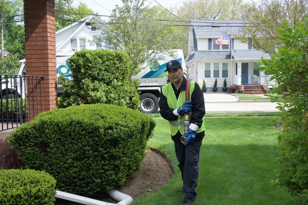Albertson, NY technician delivering heating oil near residential property with green bushes