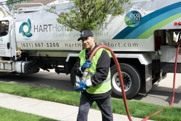Albertson, NY technician delivering heating oil with a hose from a service truck