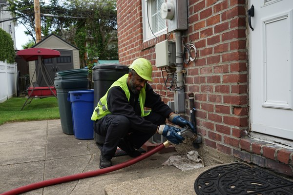 Albertson, NY technician servicing an oil burner with delivery hose at a residential property