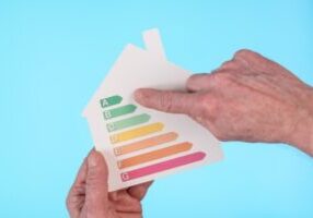 Hands holding a house cutout showing home energy efficiency rating