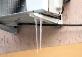 air conditioner condenser with icicle depicting frozen AC